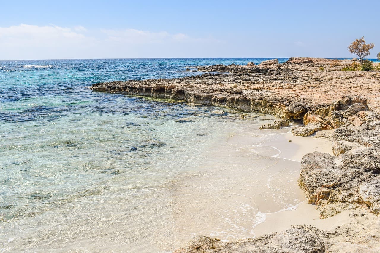A small sandy cove with shallow, clear turquoise water near Nissi Beach in Ayia Napa