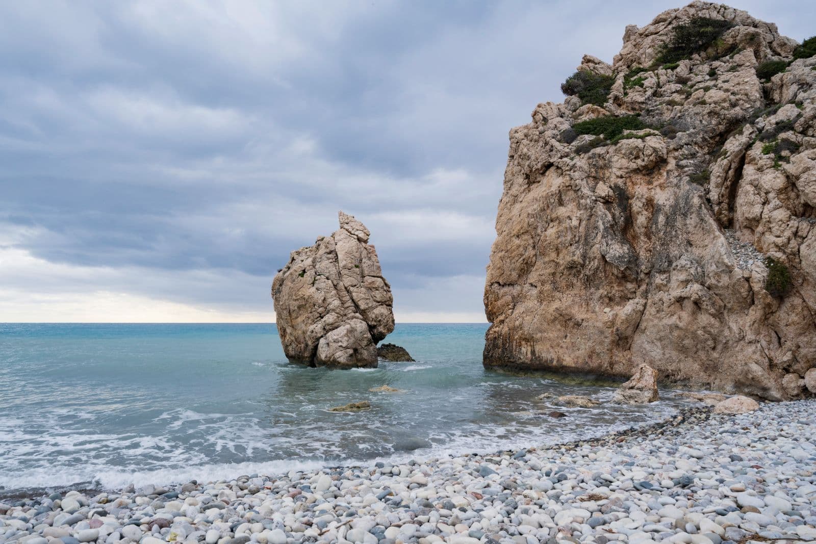 Aphrodite's Rock (Petra tou Romiou) rising from the sea off a pebble beach