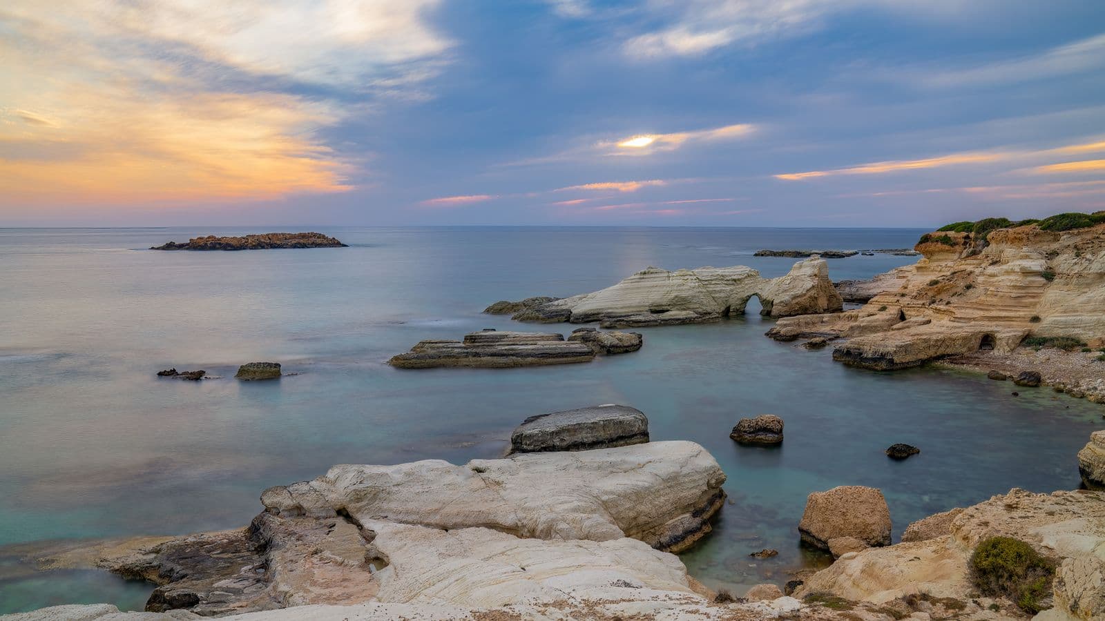 Pale rock formations and sea caves on the coast near Peyia in the Paphos district, at sunset